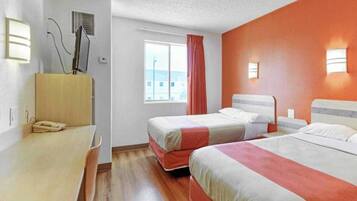 A hotel room with two beds, a desk, and a window with curtains.