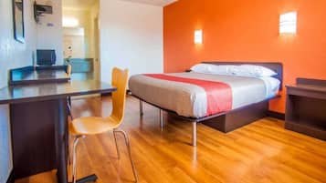 Een hotelkamer met een bed, een bureau, een stoel en een televisie.