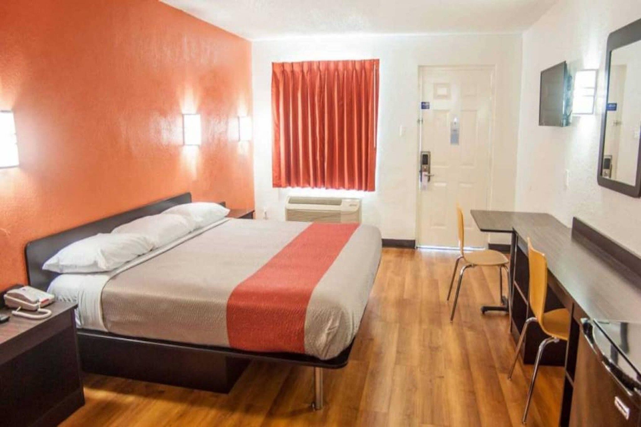 Een hotelkamer met een bed, een bureau, een stoel en een deur.