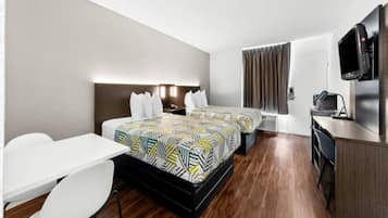 A hotel room with a bed, a desk, a chair, a TV, and a window with curtains.