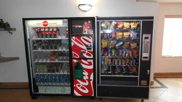 Two beverage vending machines, one with a Coca-Cola logo and the other with various snacks.
