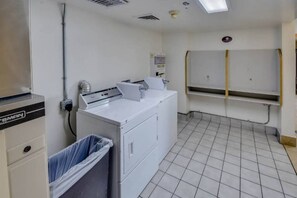 A laundry room with a washing machine, a dryer, and a trash bin. - Spacious Queen Bed| Smoking (Katy)