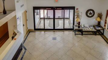 A hotel lobby with a reception desk, a coffee table, and an exit sign.