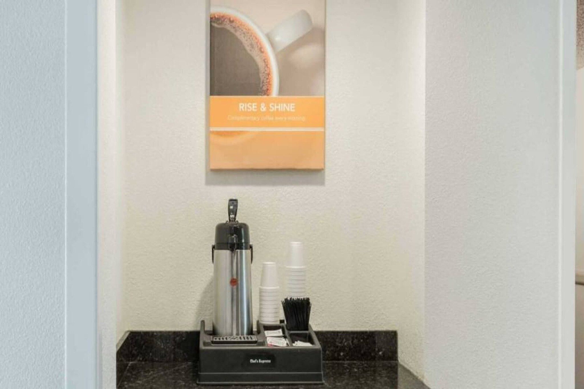 A coffee machine with disposable cups and a menu holder on a counter.
