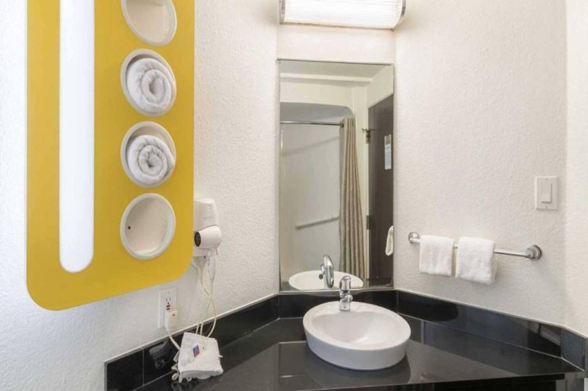 A bathroom with a black sink, a mirror, and a towel rack.