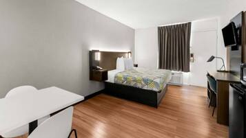 Una habitación de hotel moderna con cama, escritorio, silla y televisor.