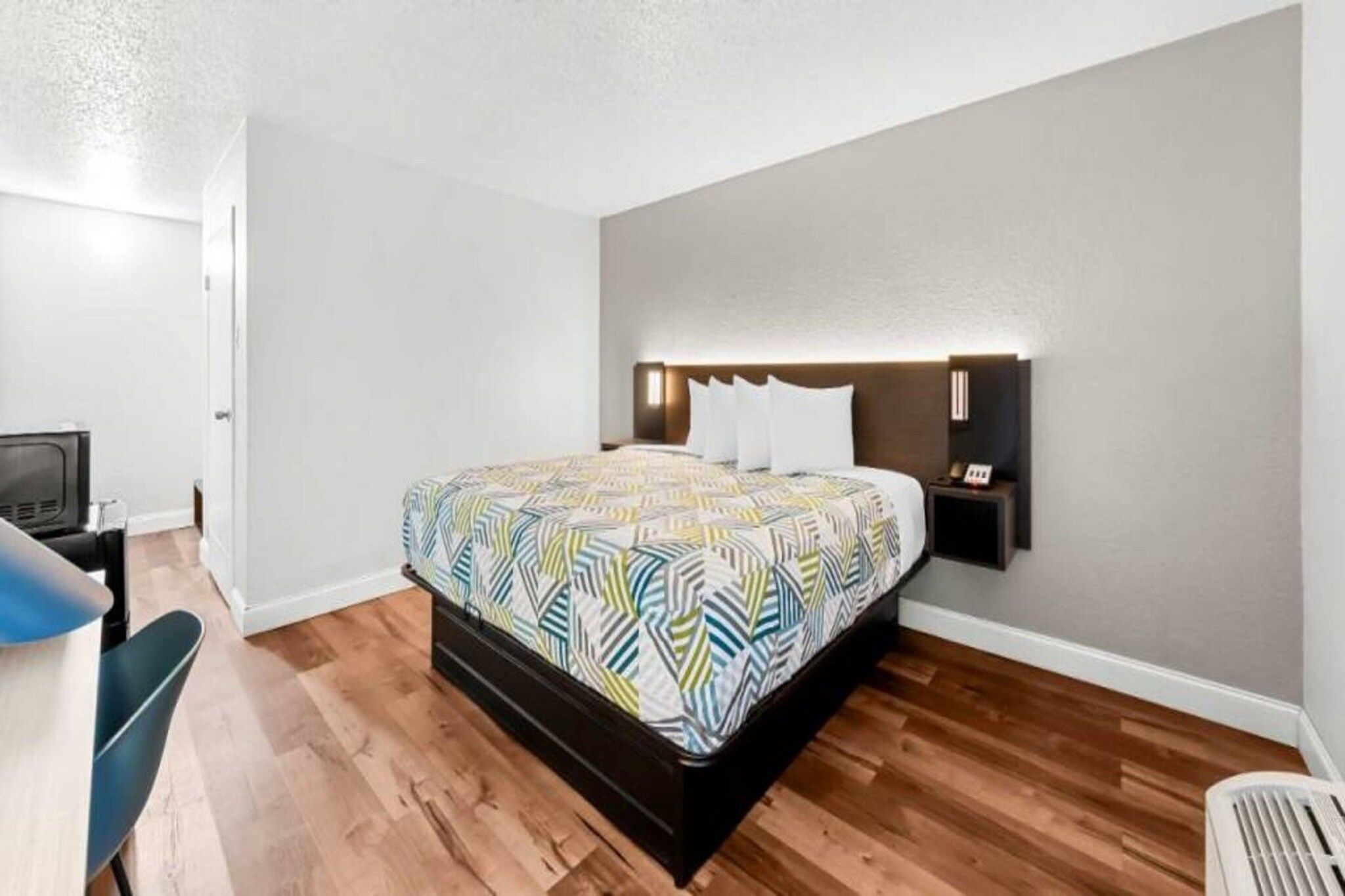 A bedroom with a bed, bedside tables, a desk, and a chair.