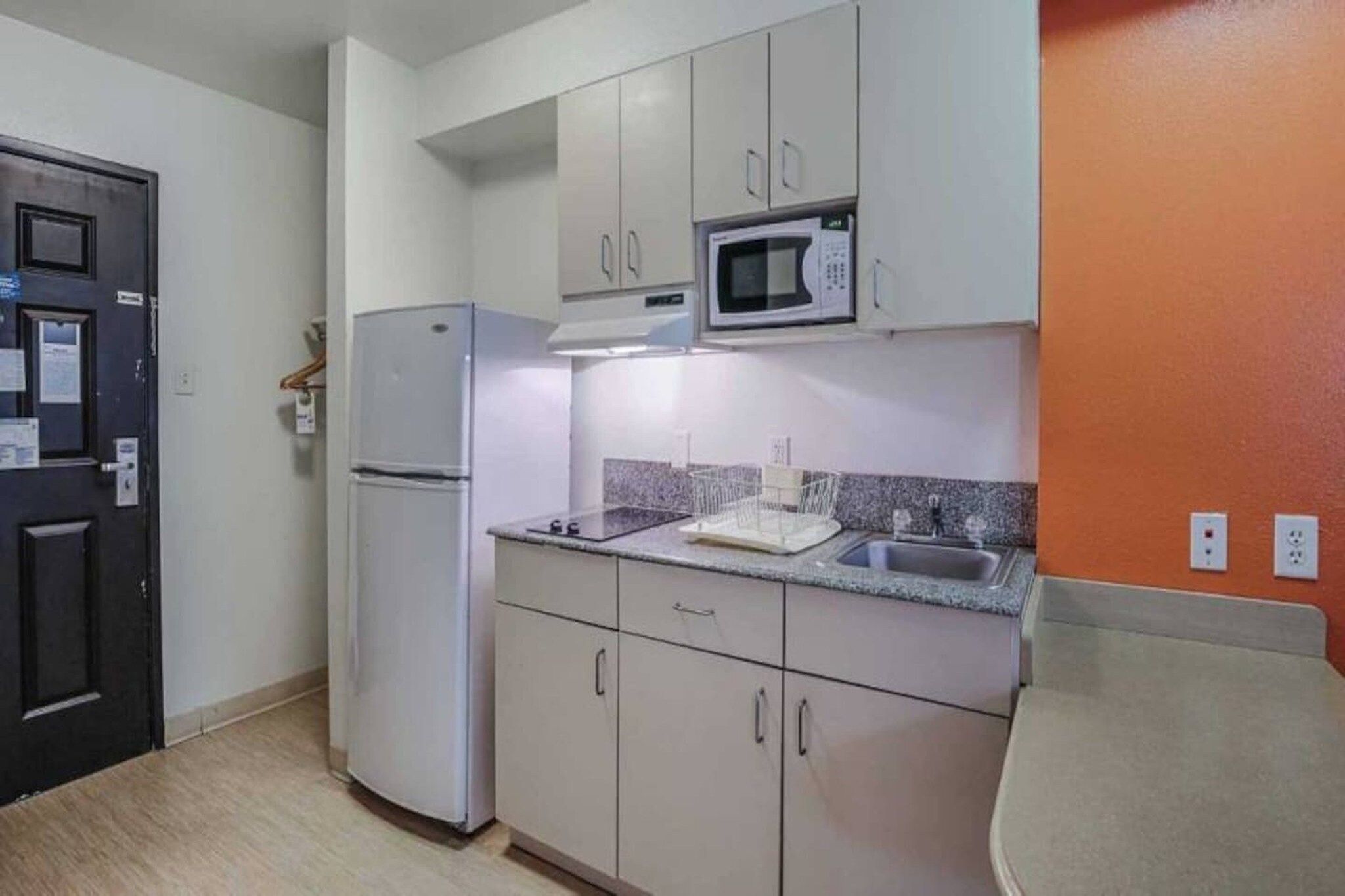 A compact kitchen with a refrigerator, microwave, and a sink.