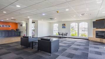 A spacious indoor area with a reception desk, seating arrangements, and large windows providing natural light.