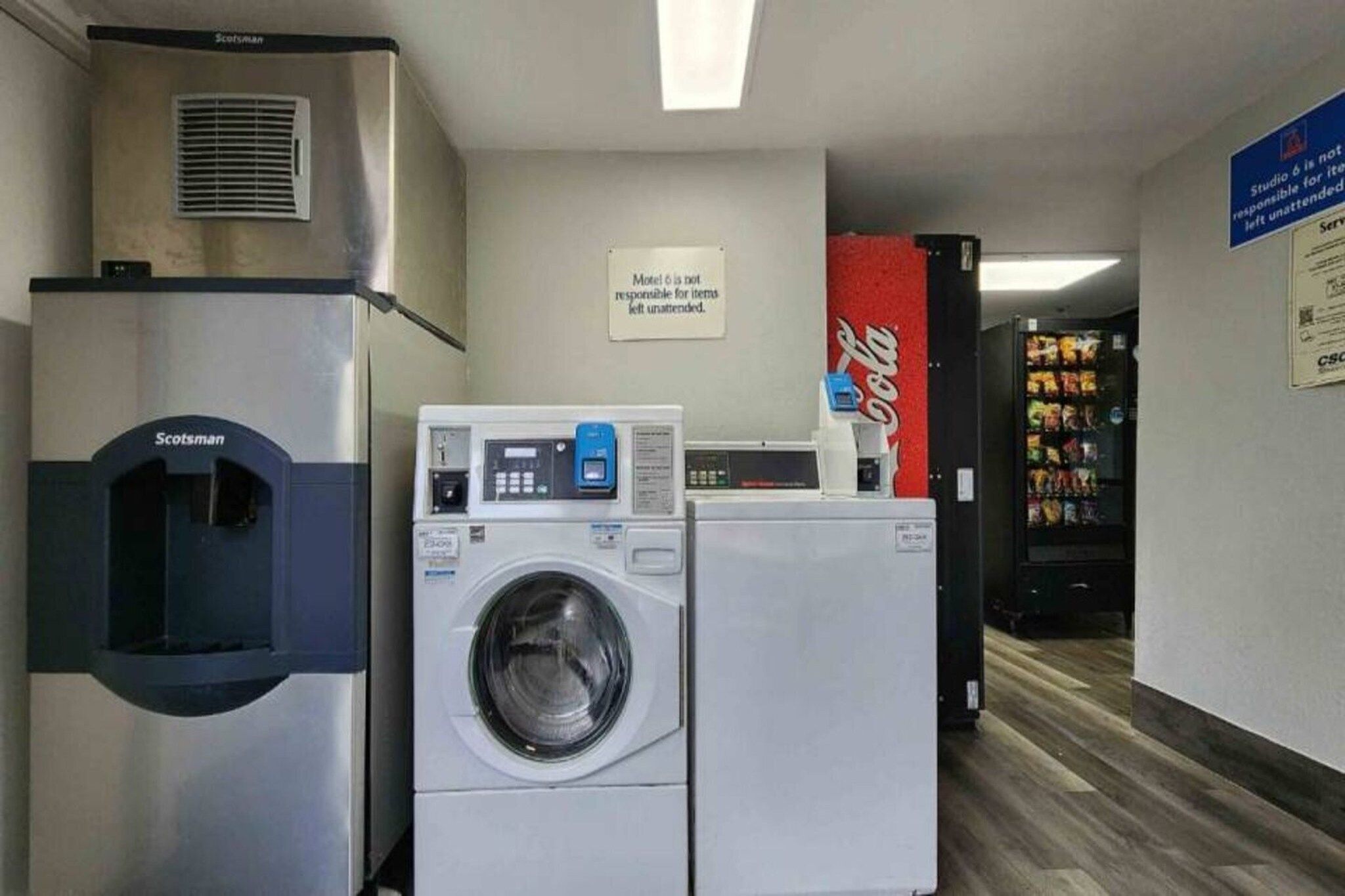 Ett tvättrum på hotellet med en torktumlare från Scotman, en tvättmaskin med frontmatning och ett kylskåp från Coca-Cola.