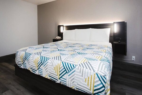 Een hotelkamer met een bed, nachtkastje en een wandlamp.