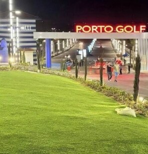 Ein gut beleuchteter Weg führt zu einem Gebäude mit dem Schild 'PORTO GOLF'.