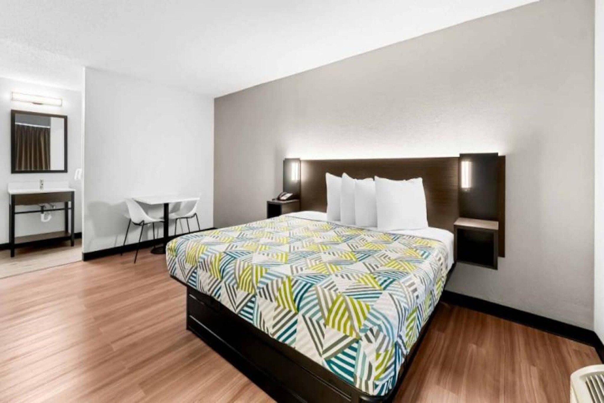 A hotel room with a large bed, bedside tables, a desk, and a chair.