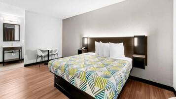 A hotel room with a large bed, bedside tables, a desk, and a chair.