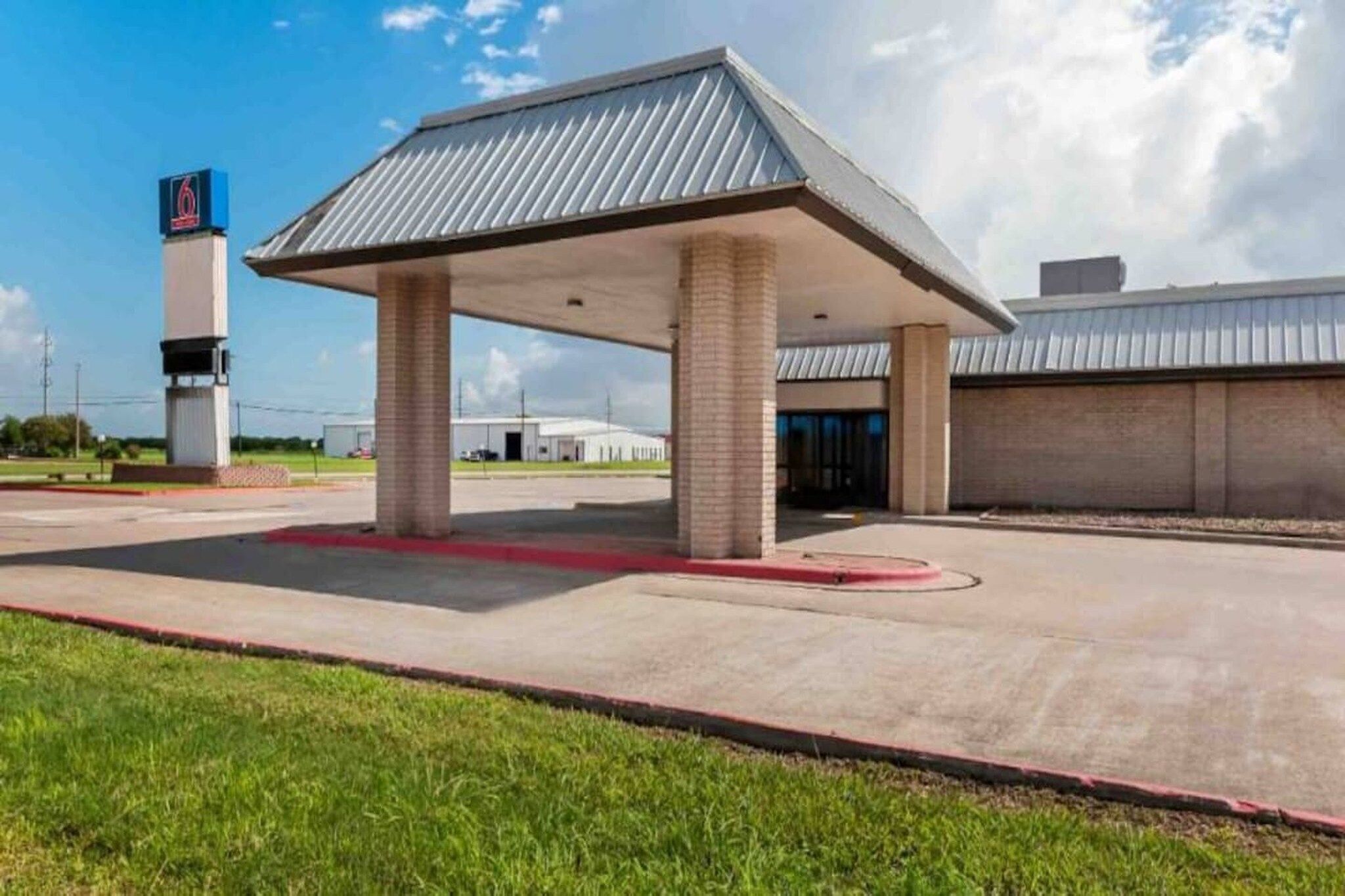 A gas station with a canopy, a fuel pump, and a building in the background.