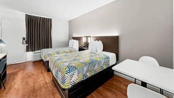 Een hotelkamer met een tweepersoonsbed, een bureau, een stoel, een kledingkast en een deur naar de badkamer.