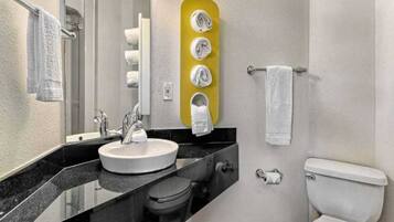 A bathroom with a sink, mirror, toilet, and towel rack.