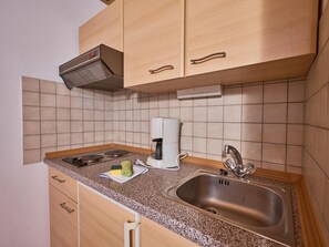 Eine Küche mit Holzschränken, einem Edelstahl-Spülbecken, einer Kaffeemaschine und einer Dunstabzugshaube.