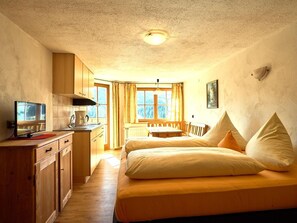 A room with a bed, a desk, a chair, a television, and a window. - Vacation Rental 8 - Almfrieden Farm (Balderschwang)