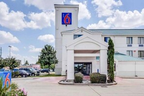 Et motel med et tydeligt skilt med nummer 6, en central indgang og en parkeringsplads.
