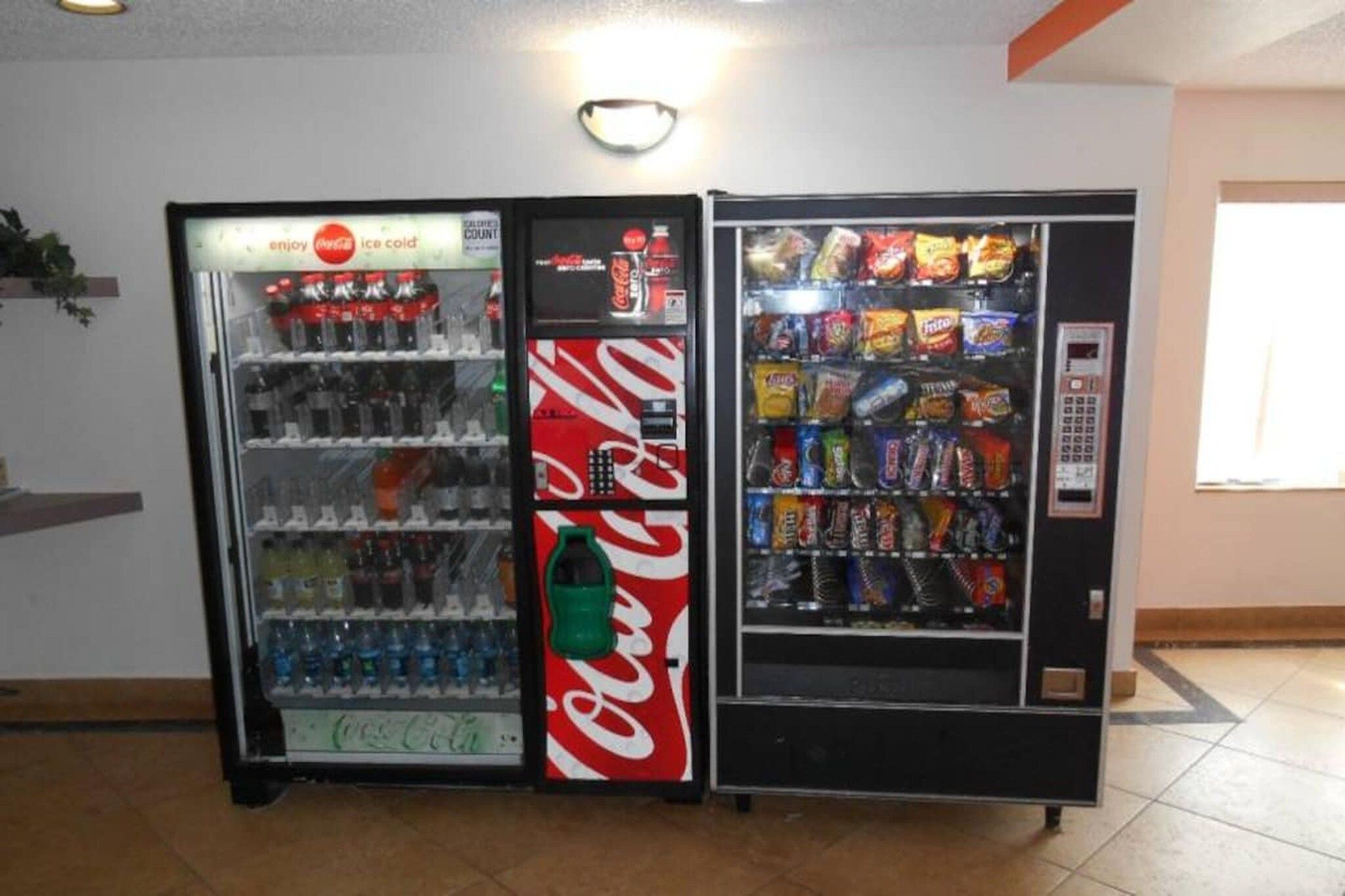 Two vending machines, one with a Coca-Cola logo and the other with various snacks.