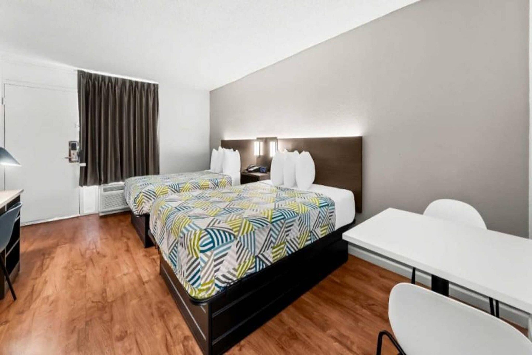 A hotel room with a double bed, a desk, a chair, a wardrobe, and a bathroom door.