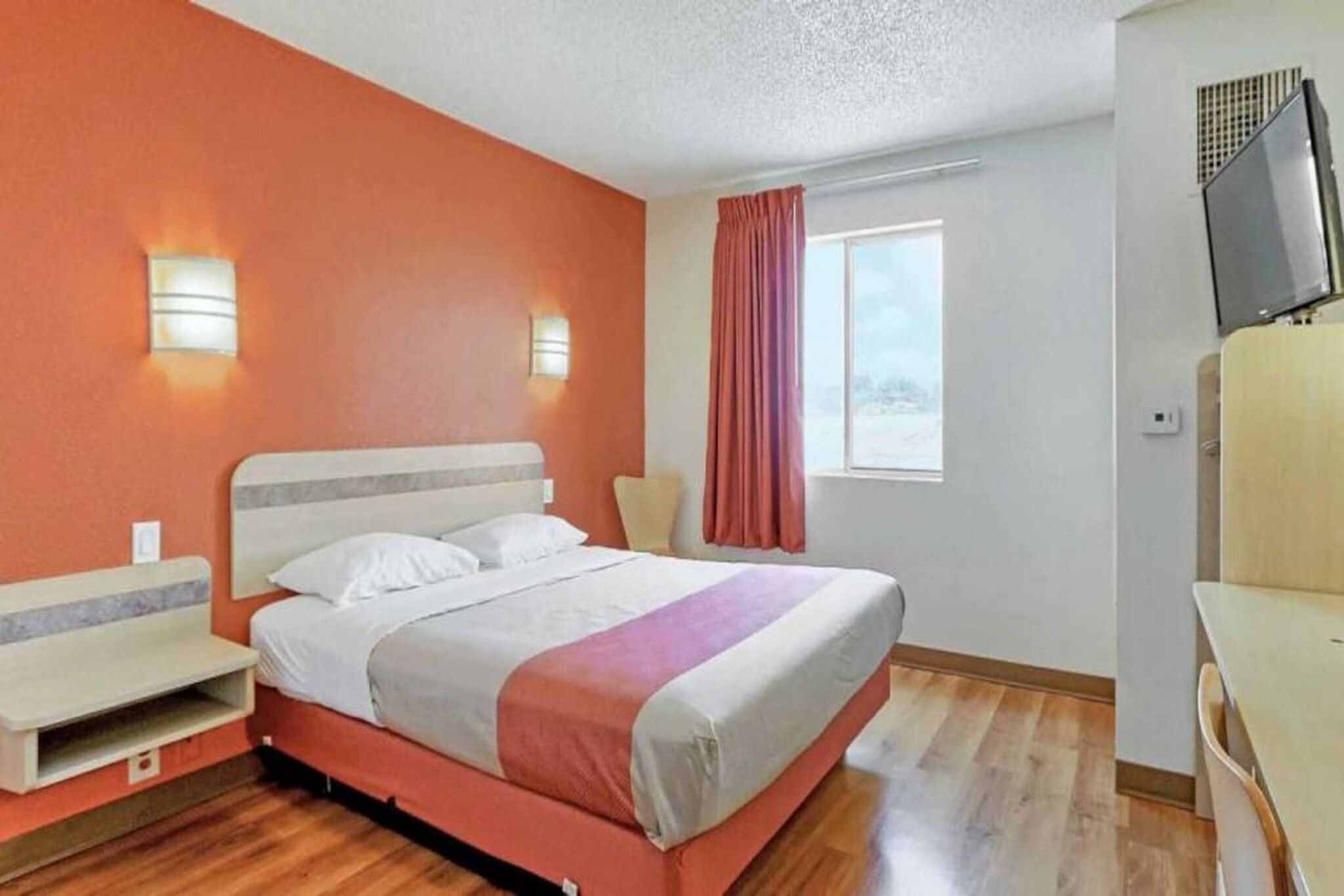 Une chambre d’hôtel avec un lit, une chaise, un bureau et un téléviseur.