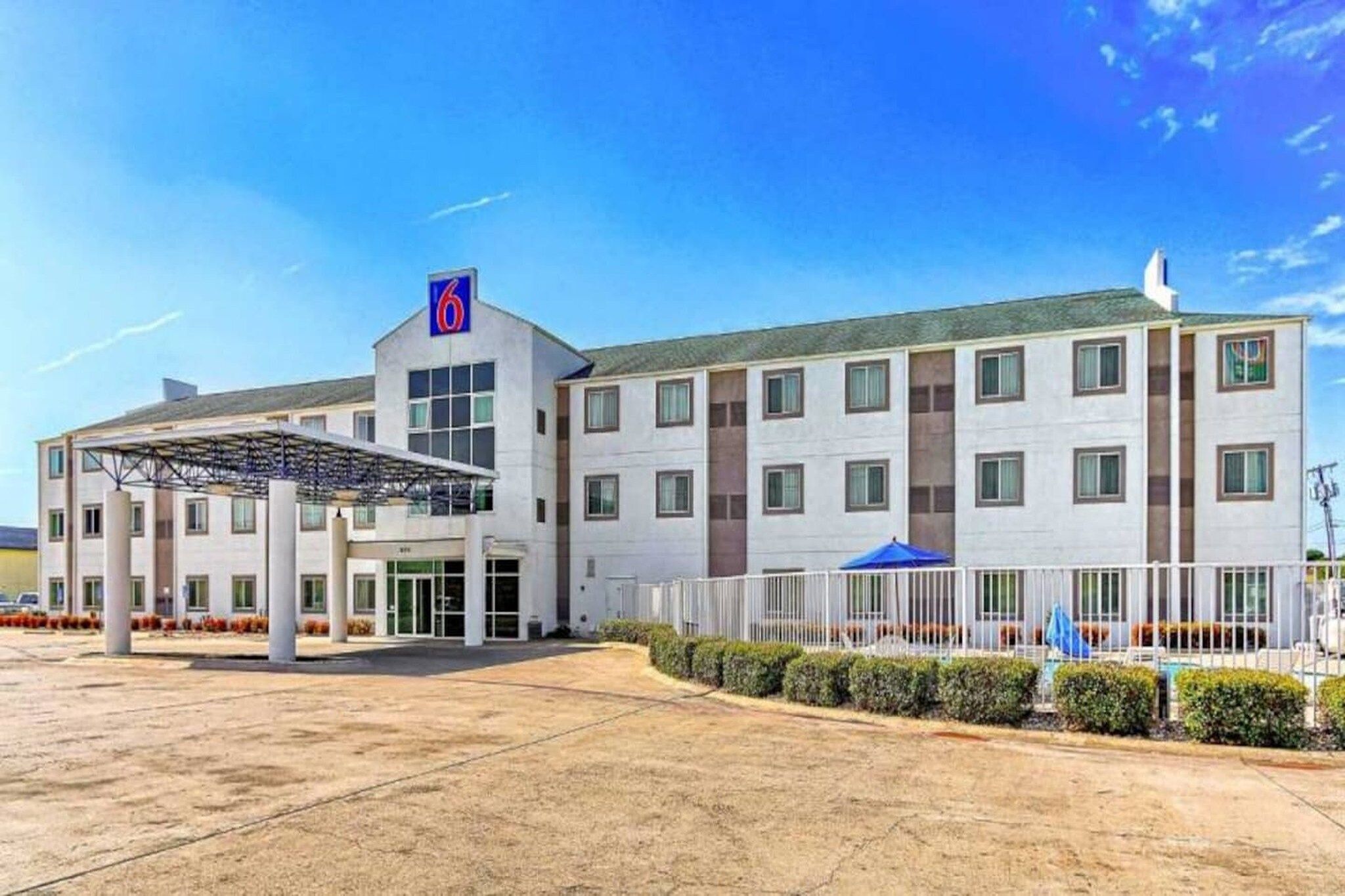A multi-story hotel with a covered entrance and a parking lot.