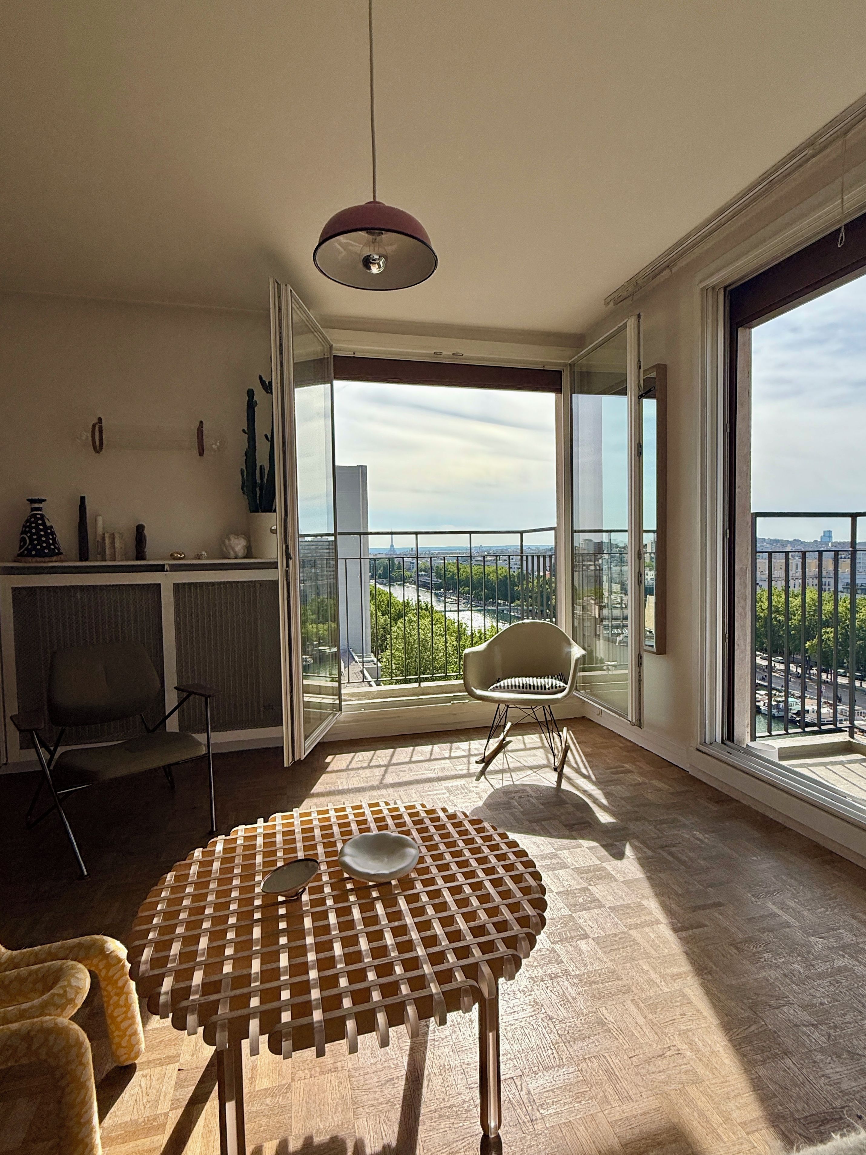 A spacious balcony with a view of the cityscape, a round table with a bowl, and a chair.