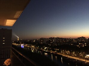 A nighttime cityscape with illuminated buildings and a river. - Chic 75 m² Apartment with Views of the Canal and the Eiffel Tower (Paris)