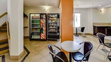 A lobby with vending machines, a staircase, and seating areas.
