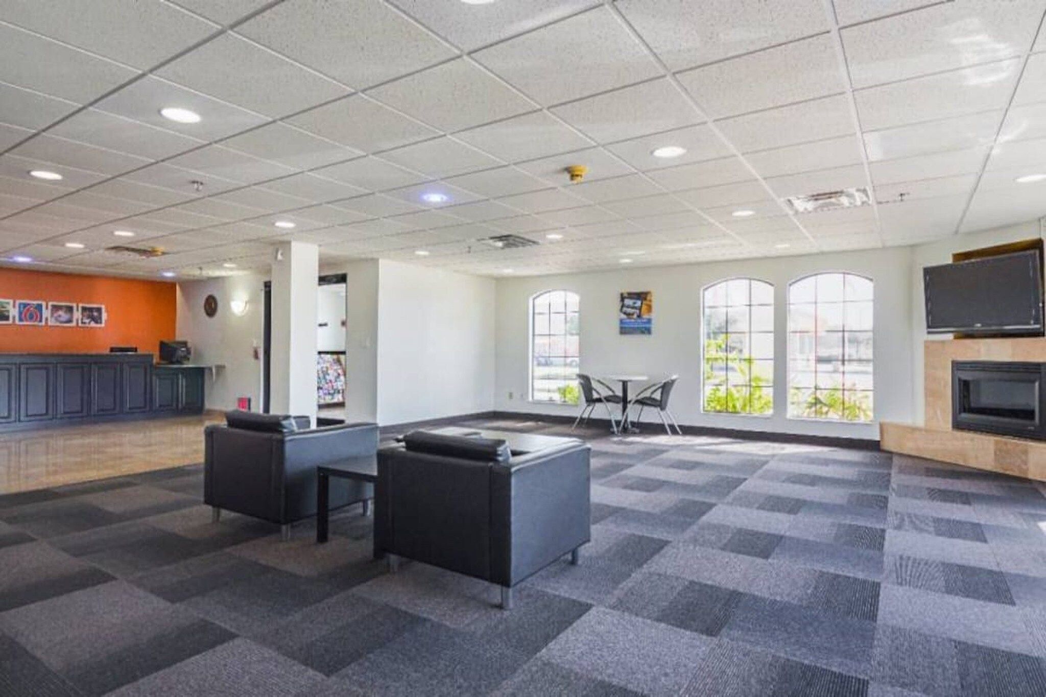 A spacious indoor area with a reception desk, seating arrangements, and large windows providing natural light.
