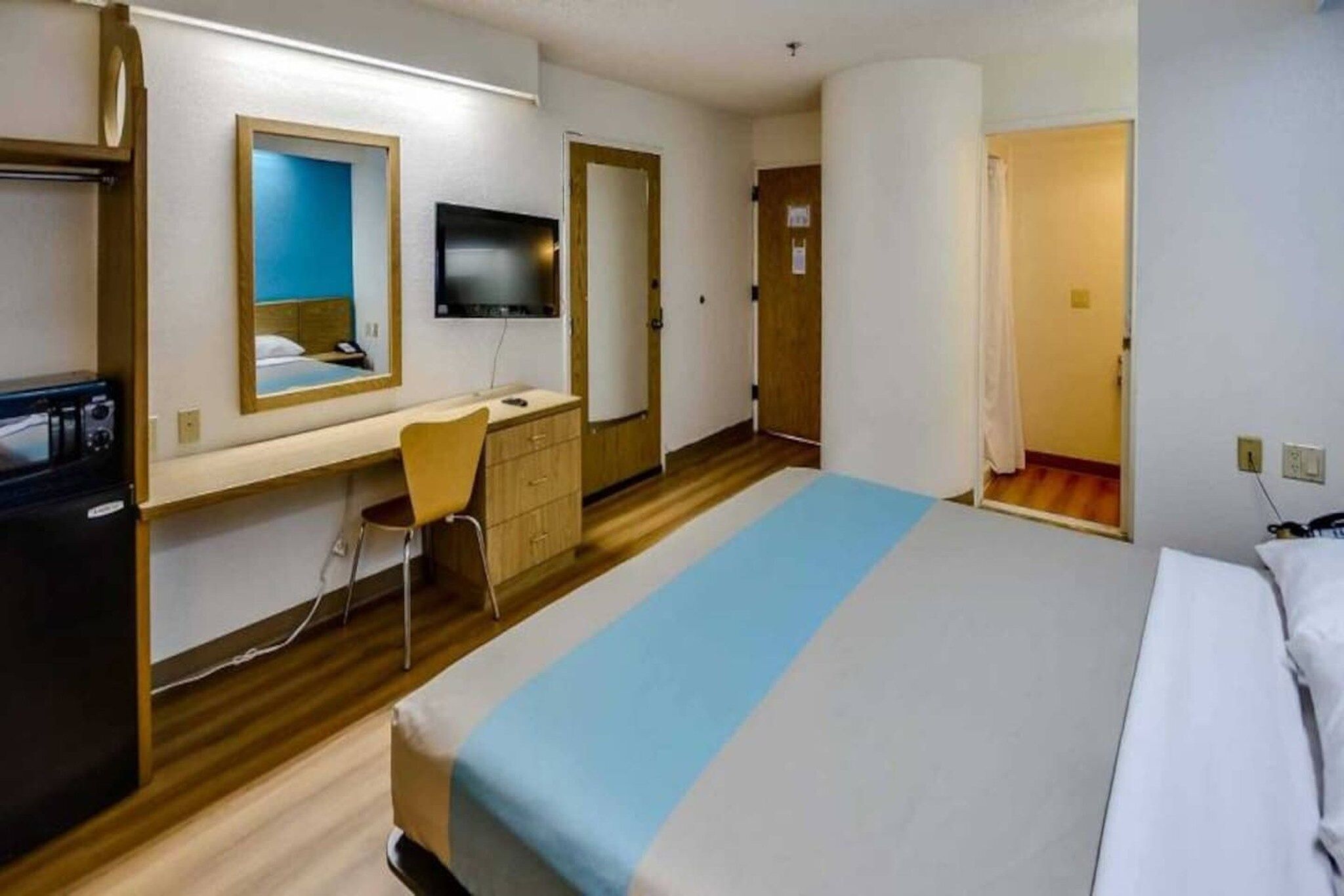 A hotel room with a bed, a desk, a chair, a television, and a wardrobe.