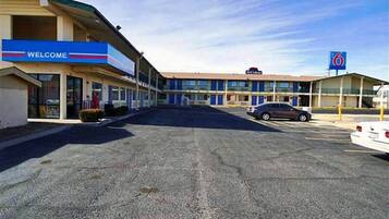 A motel with a 'WELCOME' sign, a parking lot, and a '6' sign indicating a nearby location.