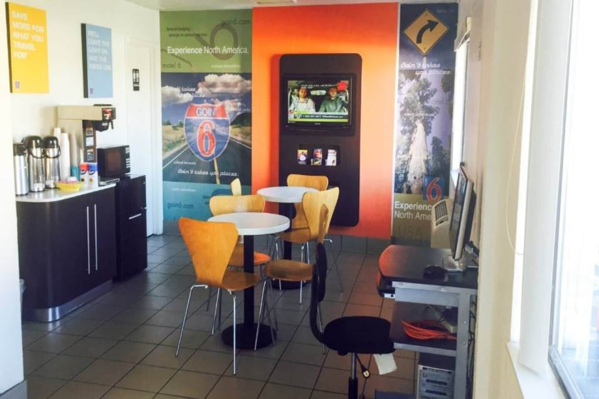 Een eetgedeelte met tafels en stoelen, een balie met een koffieapparaat, en een grote poster met de tekst 'Experience North America'.