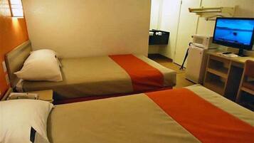 A hotel room with two beds, a desk with a computer, and a television.