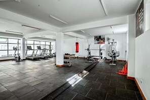 Une salle de sport équipée de tapis de course, d’appareils de musculation et d’un sac de frappe.