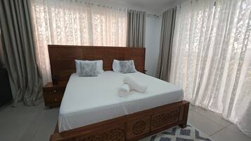 Een hotelkamer met een groot bed, een houten hoofdbord en een kamerkleed met dessin.