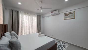 A bedroom with a bed, a ceiling fan, a window with curtains, and a framed picture on the wall.