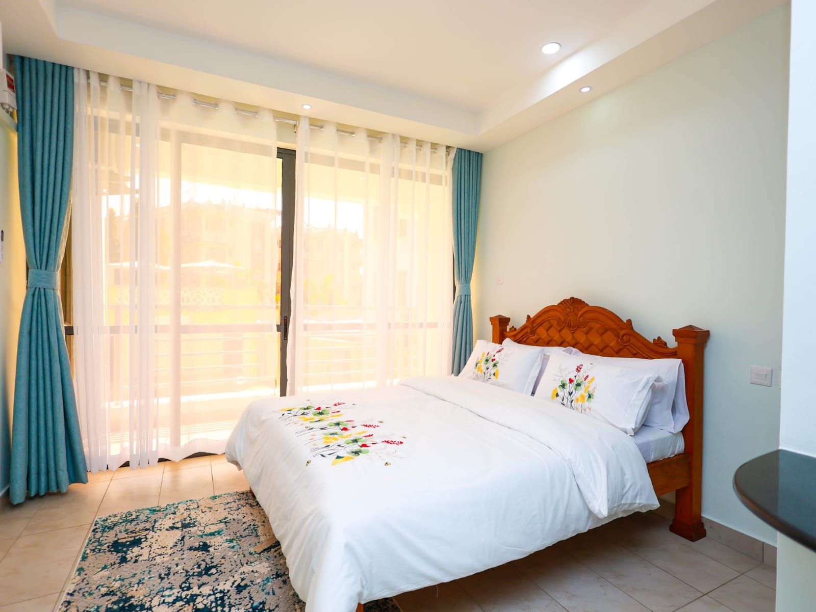 A hotel room with a bed, curtains, a window, and a small table.