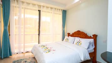A hotel room with a bed, curtains, a window, and a small table.