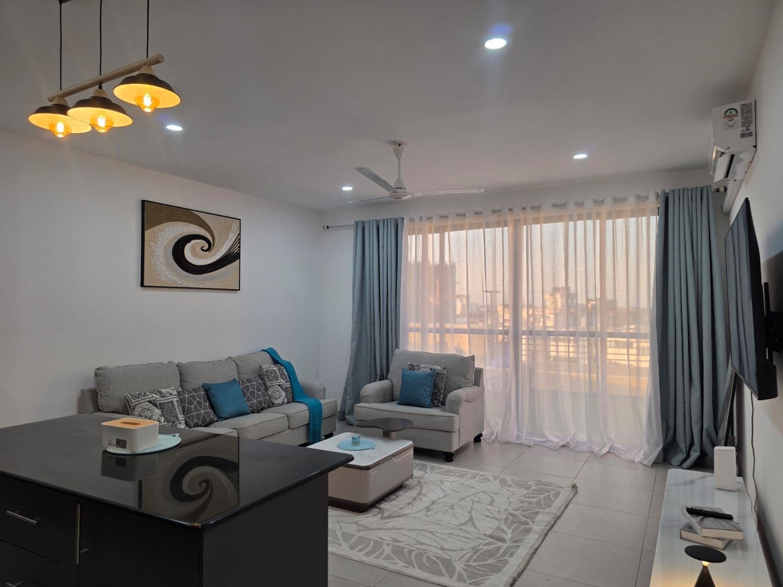 A modern living room with a sofa set, a coffee table, a TV, and a ceiling fan.