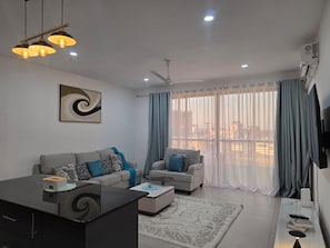 A modern living room with a sofa set, a coffee table, a TV, and a ceiling fan. - Nyali Coral Bay Apartments  (Mombasa)