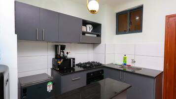 A compact kitchen with a gas stove, a coffee maker, and a sink.