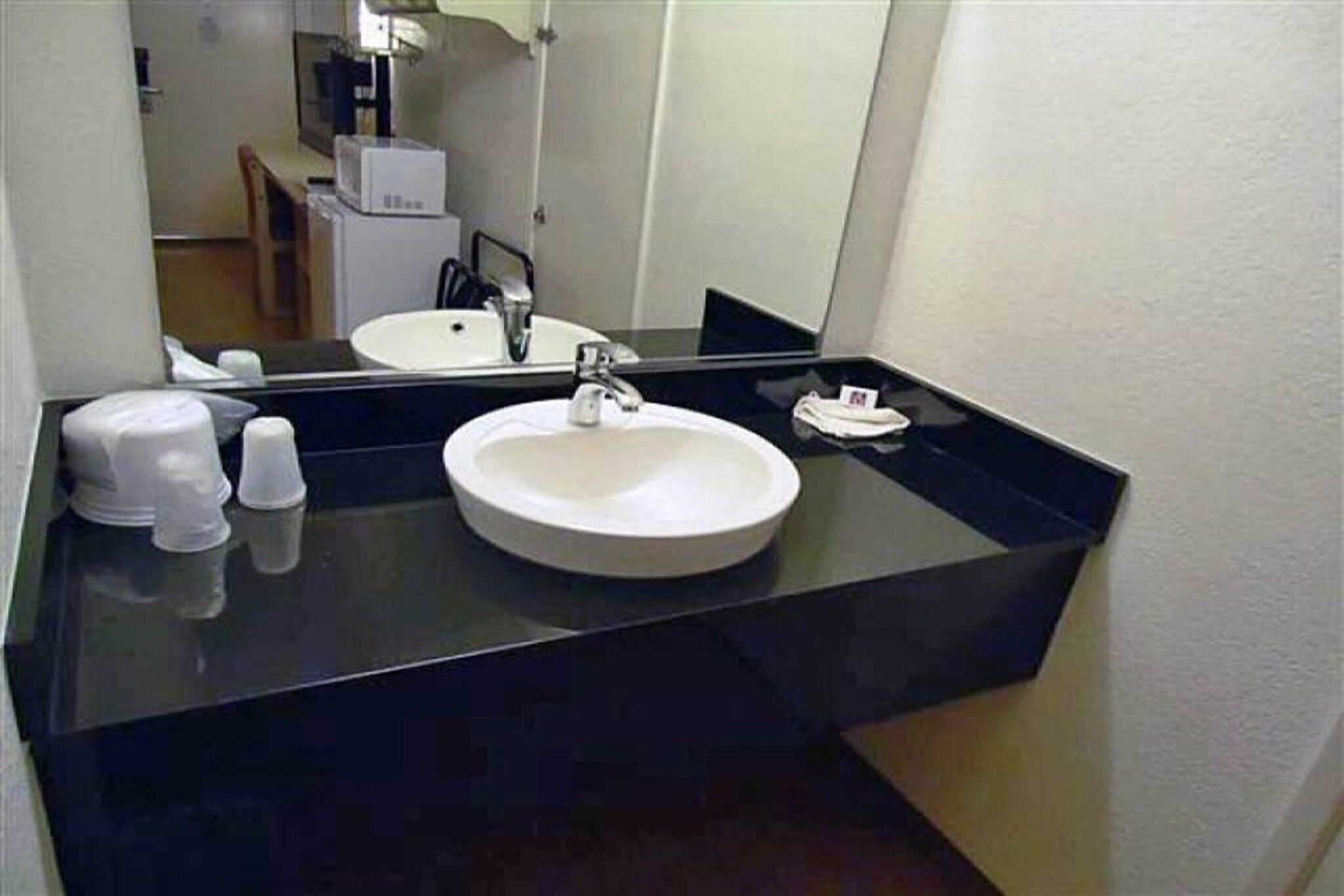 Een badkamer met een wit wastafel, een zwart aanrecht en een spiegel boven de wastafel.