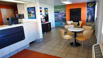 A restaurant with a counter, chairs, and tables.