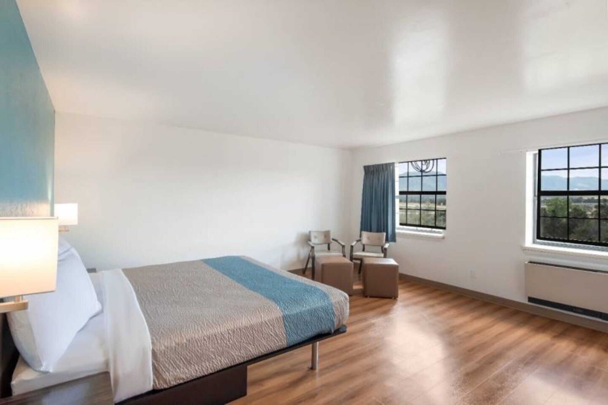 Una habitación de hotel con una cama, un escritorio, una silla y vistas al exterior a través de la ventana.