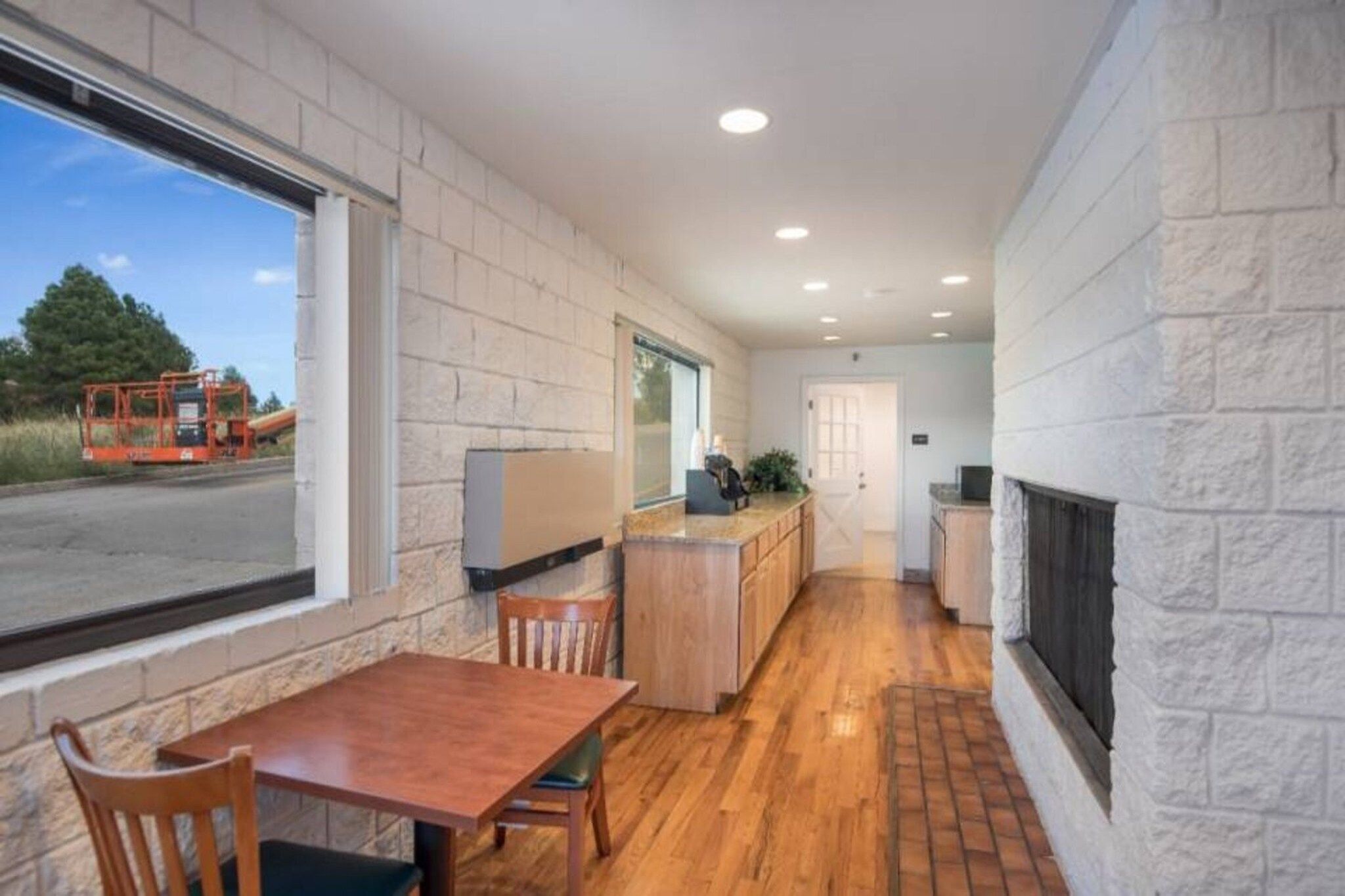 A modern kitchen with a wooden countertop, a dining area with a table and chairs, and a large window overlooking a street.