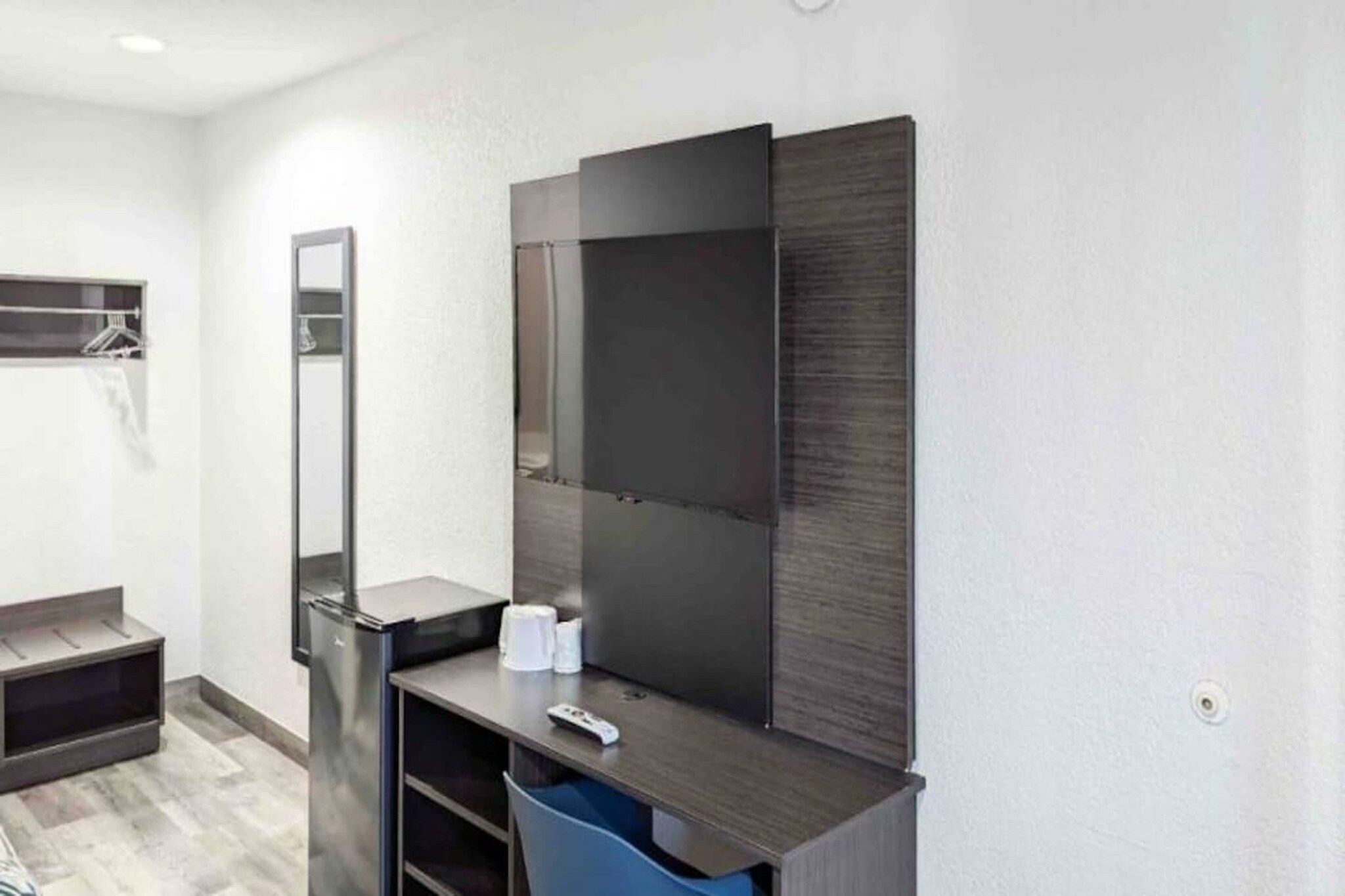 A modern bathroom with a large mirror, a vanity with a sink, and a trash bin.