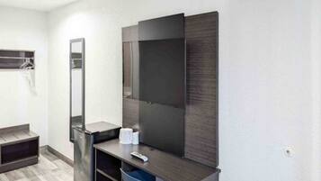 A modern bathroom with a large mirror, a vanity with a sink, and a trash bin.